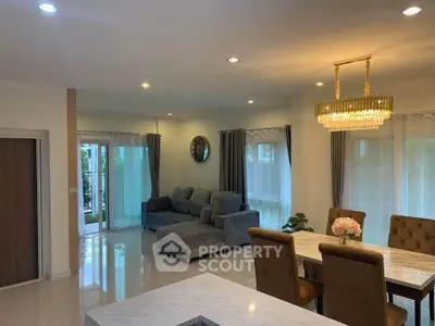 Elegant living and dining area with modern chandelier and cozy seating.