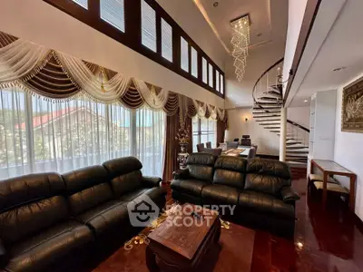 Luxurious living room with high ceilings, elegant drapes, and spiral staircase