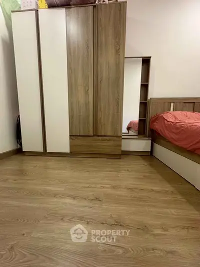 Modern bedroom with sleek wooden wardrobe and cozy bed setup.