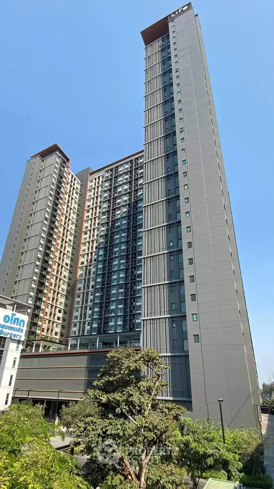Modern high-rise residential building with sleek design and lush greenery, perfect for urban living.