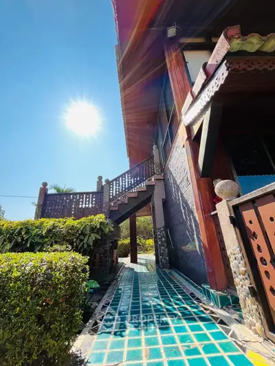 Stunning exterior view of a sunlit property with vibrant tiled pathway and lush greenery.