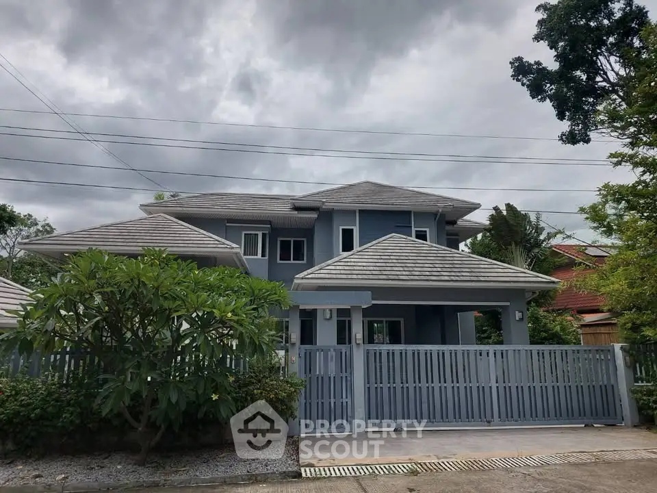 Charming two-story blue house with lush greenery and modern design in a serene neighborhood.