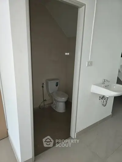 Compact bathroom with toilet and wall-mounted sink in modern apartment.