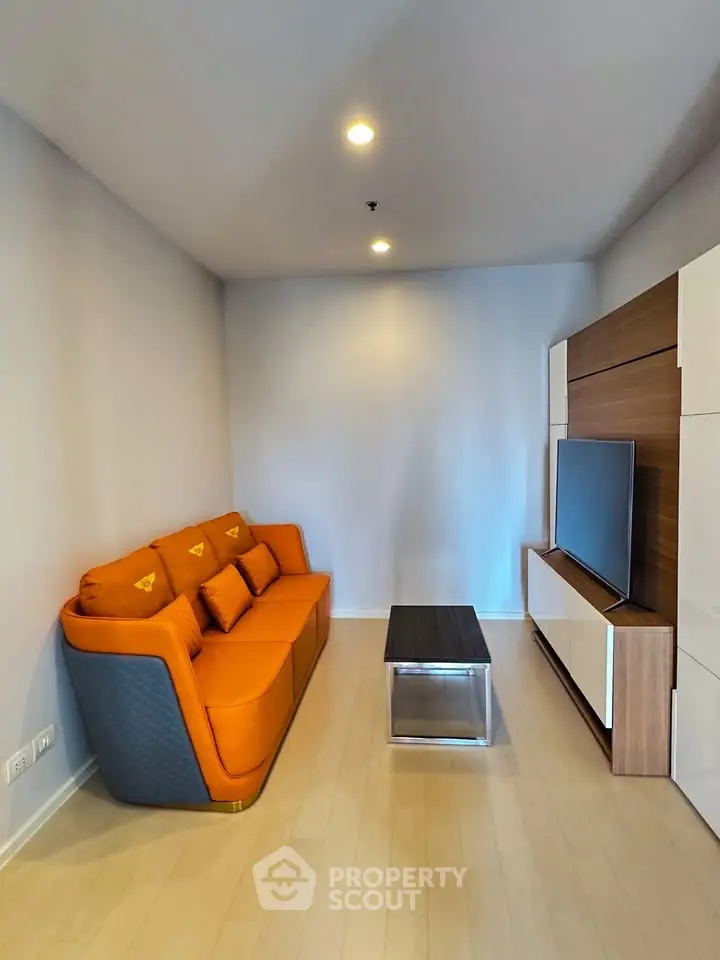 Modern living room with vibrant orange sofa and sleek TV unit