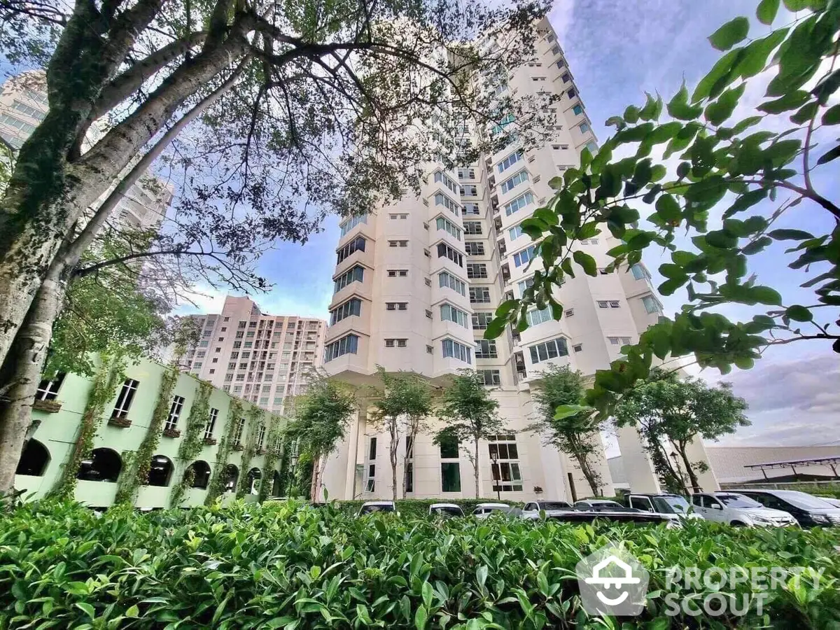 Lush greenery frames the elegant facade of this modern high-rise residential building, offering a serene urban living experience amidst nature.