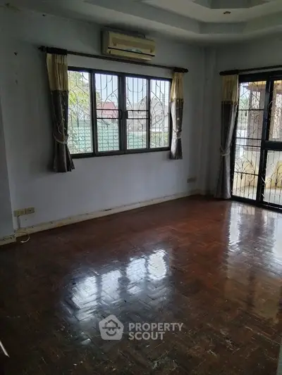 Spacious empty room with polished wooden floors and large windows