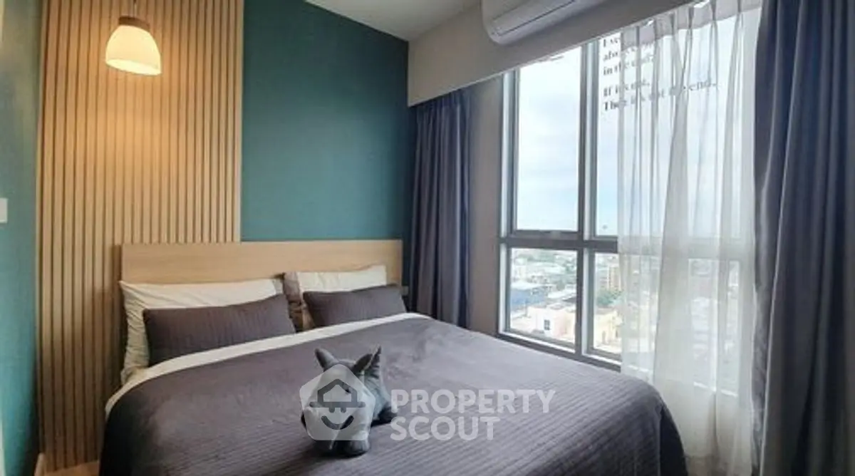 Cozy bedroom with large window and modern decor in urban apartment.