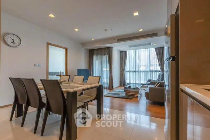 Spacious modern living room with dining area and large windows in a luxury apartment.