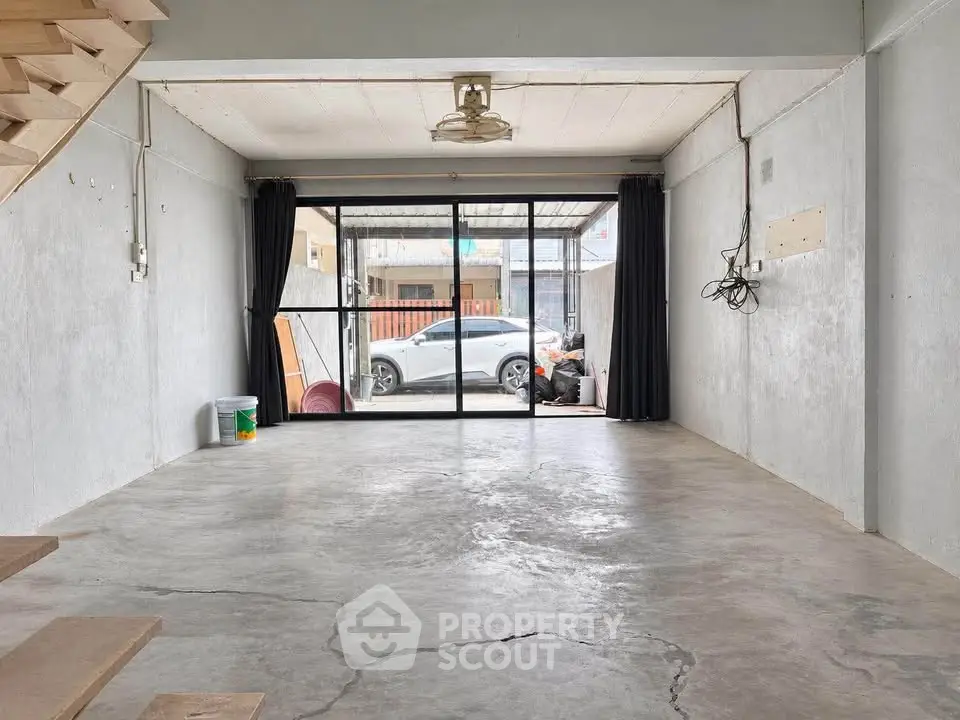 Spacious unfinished room with large sliding glass doors and concrete flooring, ideal for customization.