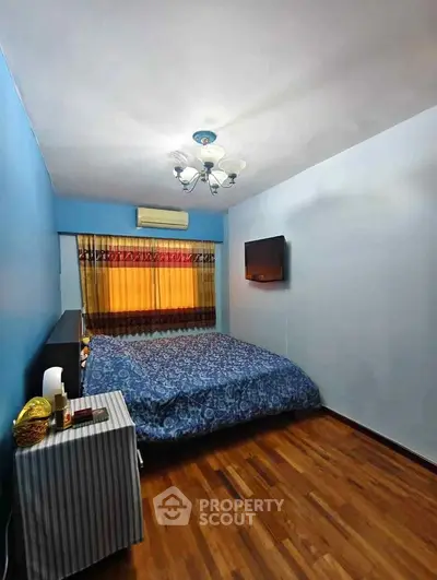 Cozy bedroom with wooden flooring and wall-mounted TV in a modern apartment.