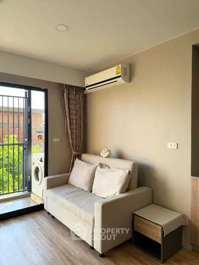 Cozy living room with sofa and air conditioning, featuring a balcony view and washing machine.