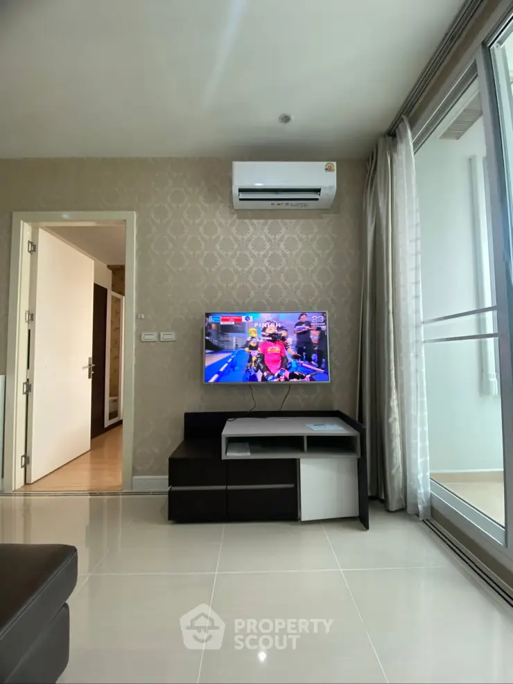 Modern living room with TV and air conditioning, featuring elegant wallpaper and sliding glass doors.