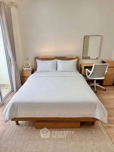 Modern bedroom with wooden furniture and natural light, featuring a cozy bed and study area.