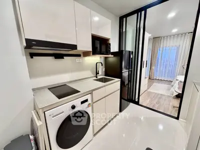 Modern kitchen with sleek appliances and open layout leading to a cozy bedroom.