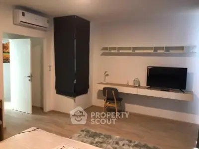Modern bedroom with wall-mounted TV and sleek workspace in stylish apartment.