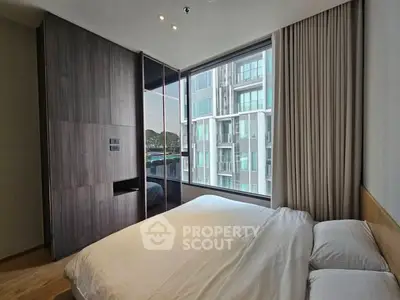 Modern bedroom with large window offering city view in luxury apartment