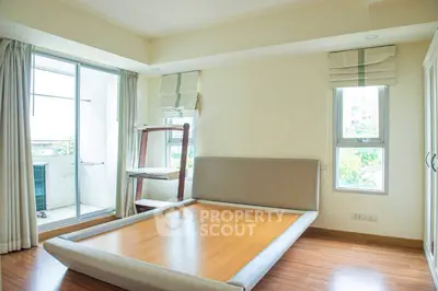 Spacious bedroom with large windows and balcony access in modern apartment
