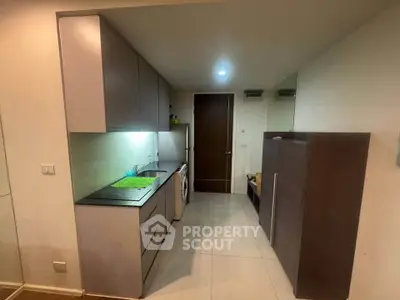 Modern kitchen with sleek cabinetry and built-in washing machine in compact apartment.