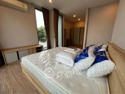 Spacious bedroom with large windows and modern furnishings in a serene setting.