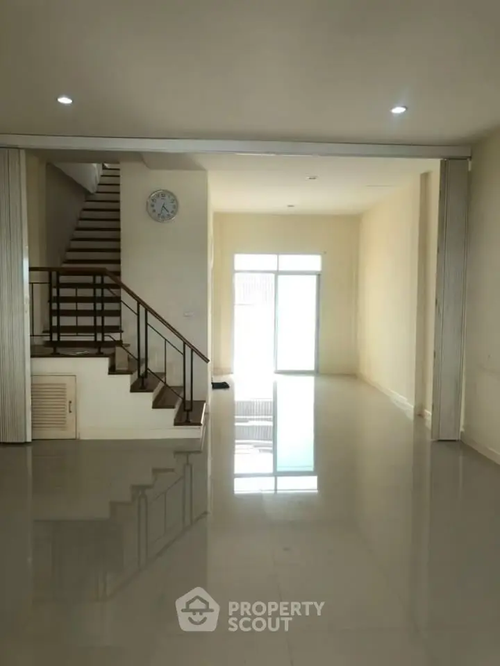 Spacious modern living room with glossy floors and staircase, perfect for stylish urban living.