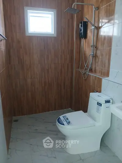 Modern bathroom with sleek shower and toilet, featuring stylish wood and marble tile design.