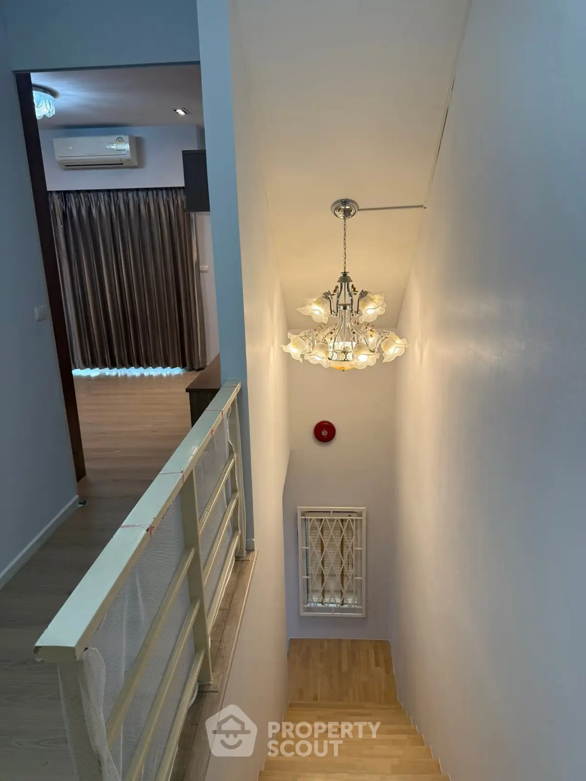 Elegant staircase with modern chandelier and view into a cozy room with air conditioning.