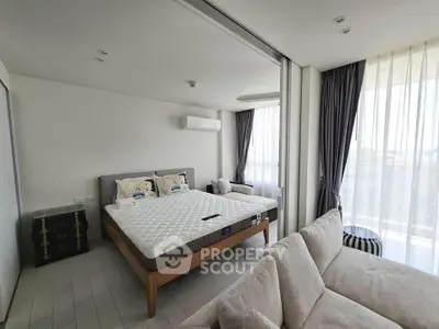 Spacious bedroom with modern decor and large windows offering natural light.
