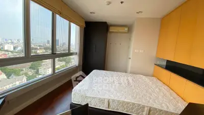 Modern bedroom with large windows offering stunning city views and ample natural light.
