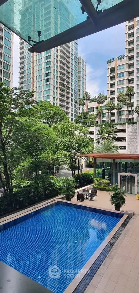 Luxurious condominium with a stunning pool and lush greenery, offering a serene urban oasis.
