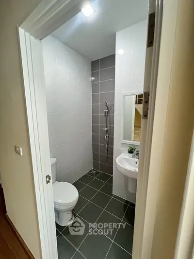 Modern bathroom with sleek design, featuring a shower, toilet, and sink in a compact layout.