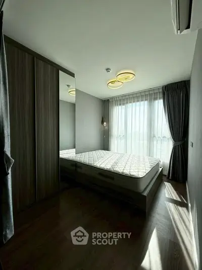 Modern bedroom with large window and stylish lighting in a contemporary apartment.