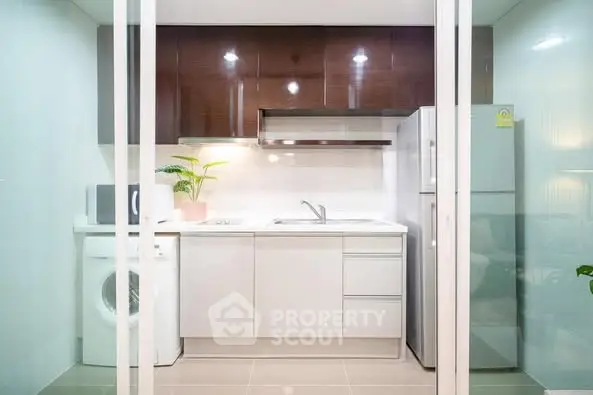 Modern compact kitchen with sleek white cabinets and appliances
