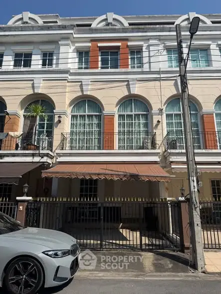 Elegant townhouse with arched windows and gated entrance in urban setting