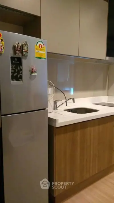 Modern kitchen with sleek cabinets and stainless steel fridge in a stylish apartment.