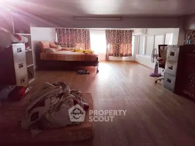 Spacious bedroom with wooden flooring and large windows for natural light.