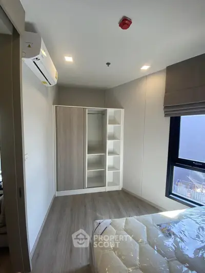Modern bedroom with built-in wardrobe and air conditioning in a bright apartment.