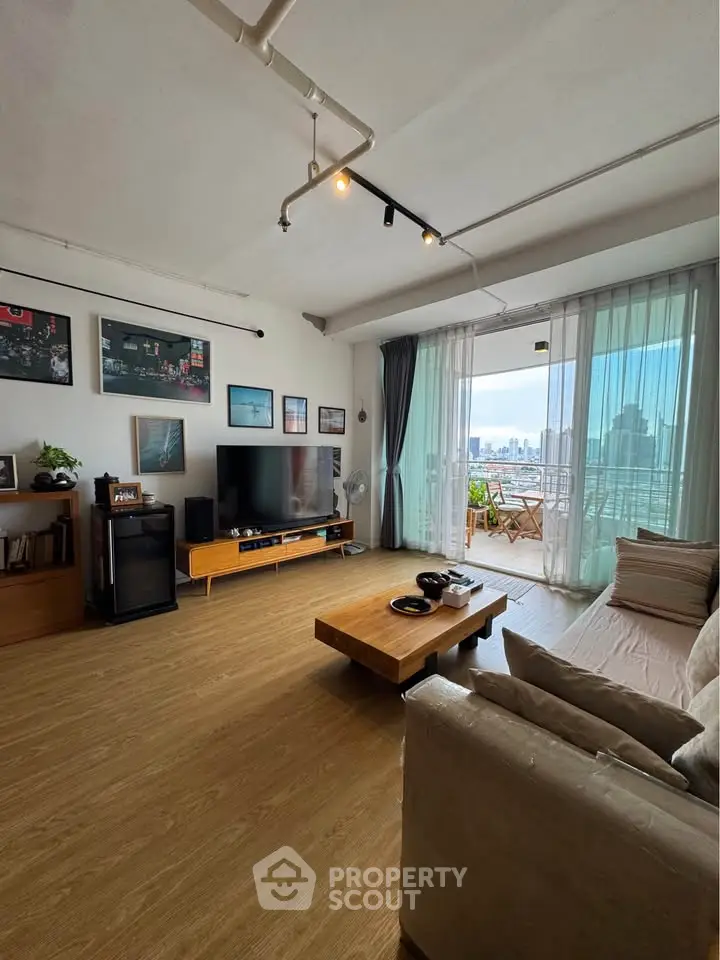 Spacious living room with modern decor and city view balcony, perfect for urban living.