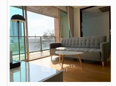 Spacious living room with modern sofa and large balcony offering city views.