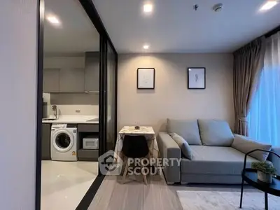 Modern living room with open kitchen and washing machine, cozy sofa, and dining area.