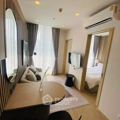 Modern living room with stylish decor and natural light, featuring a cozy sofa and wall-mounted TV.