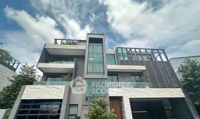 Modern multi-story building with sleek design and large windows under a cloudy sky.