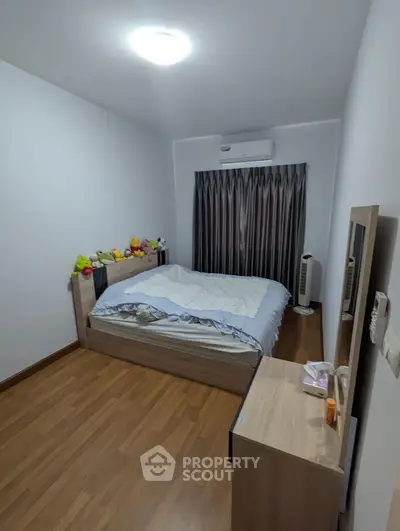 Cozy bedroom with wooden flooring and air conditioning, perfect for restful nights.