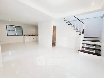 Spacious open-plan living area with modern staircase and tiled flooring