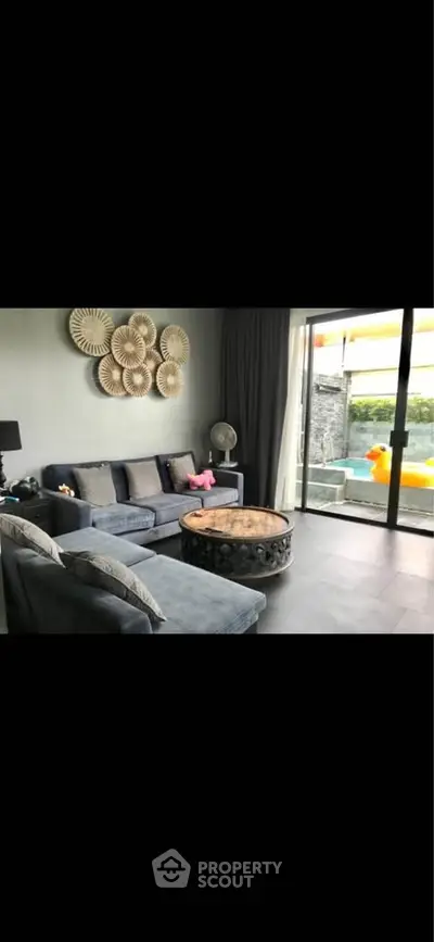 Stylish living room with modern decor and pool view, featuring cozy seating and elegant wall art.
