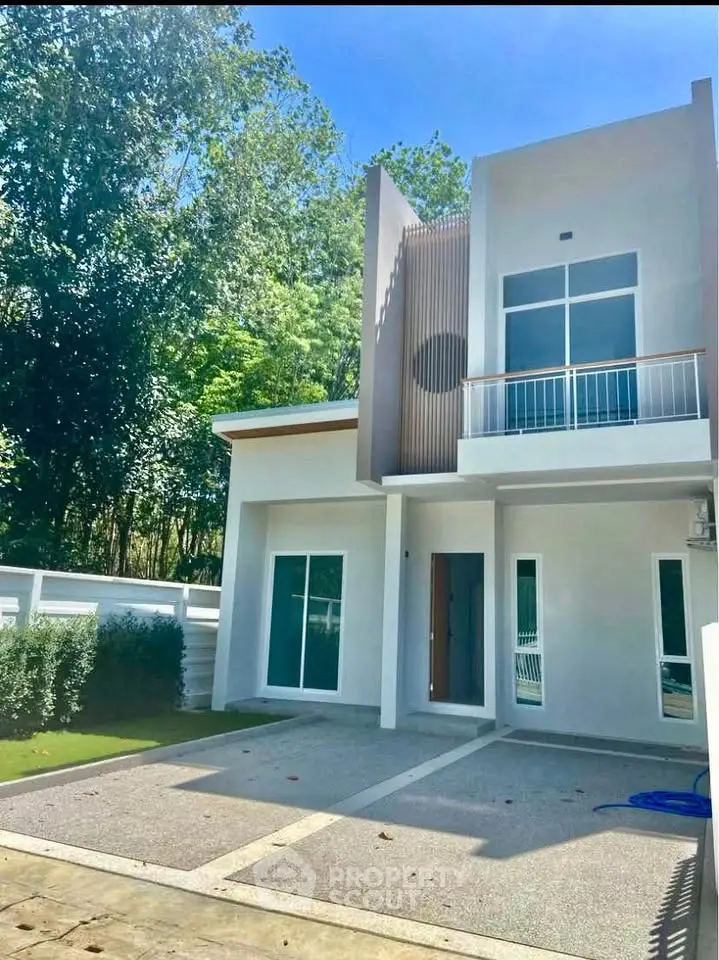 Modern two-story house with sleek design and spacious driveway in a lush green setting.