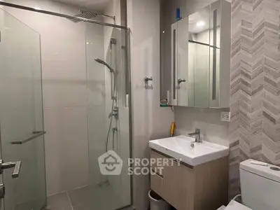 Modern bathroom with glass shower and sleek vanity in contemporary apartment.