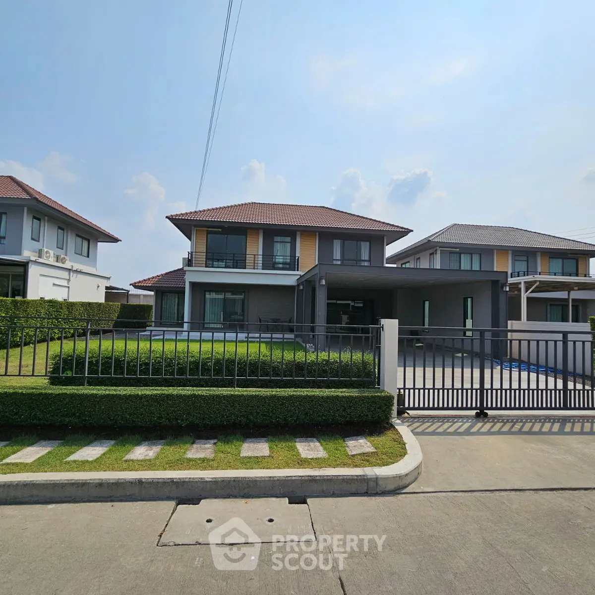 Modern two-story house with manicured lawn and gated driveway in suburban neighborhood.