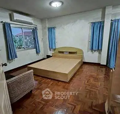 Spacious bedroom with wooden flooring and natural light