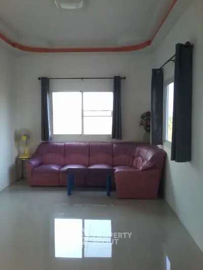 Spacious living room with pink sofa and large windows for natural light.