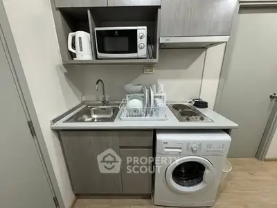 Compact kitchen with modern appliances including washing machine and microwave in a stylish apartment.
